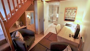 A cozy room with a wooden staircase, a small seating area with a table and chairs, and a shower area visible through an open door. - Centre of Britain Hotel & Restaurant (Haltwhistle)