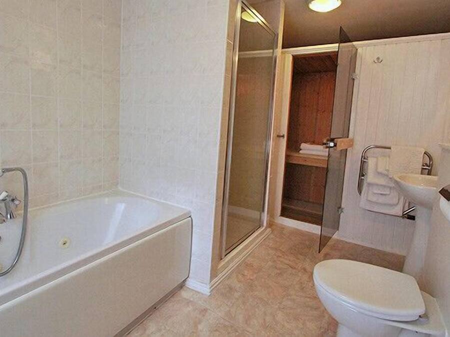 A bathroom with a bathtub, toilet, and a glass-enclosed shower area.