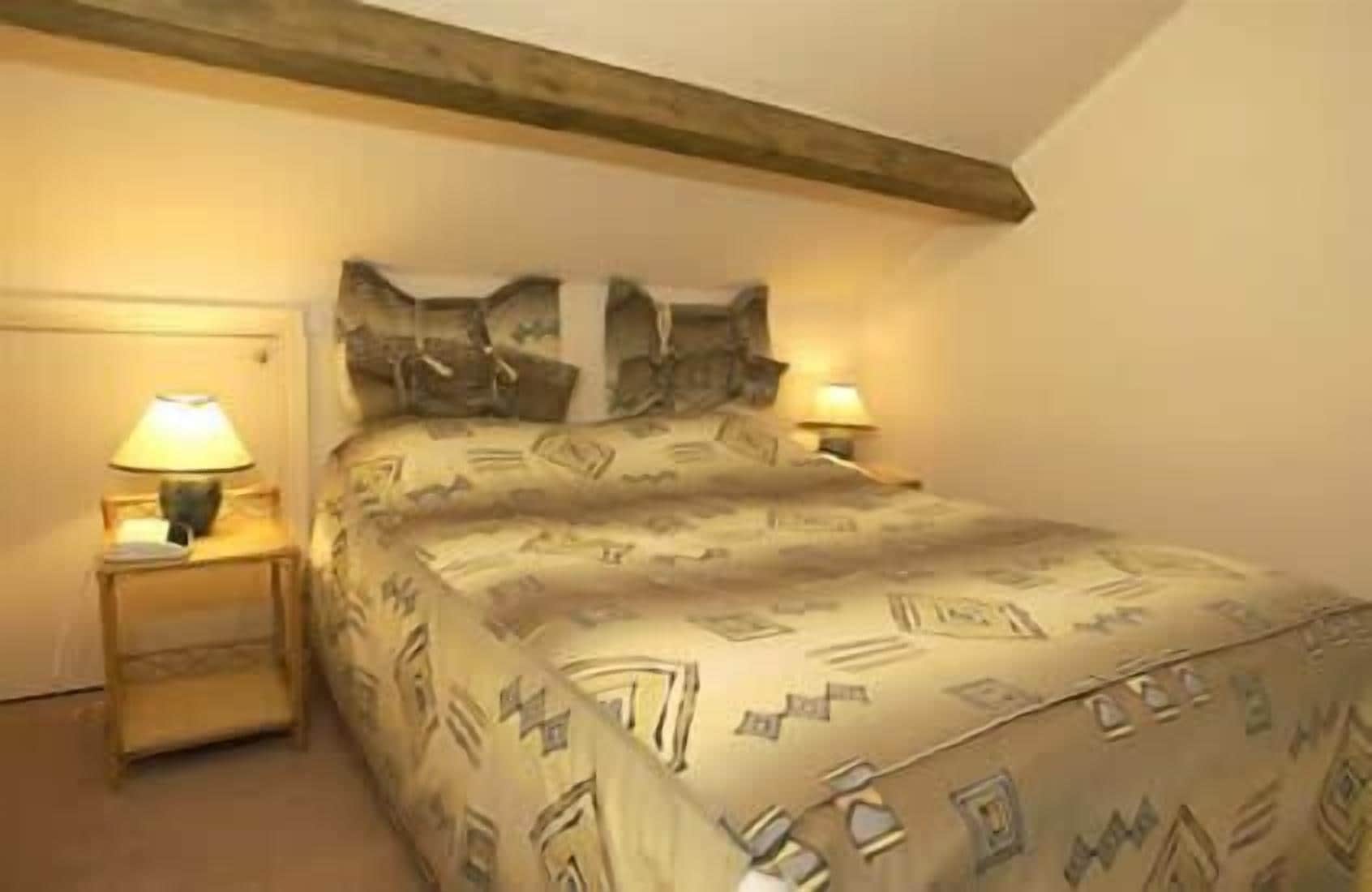 A bedroom with a bed, two bedside tables, and two lamps.