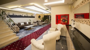 A spacious living area with a red carpet, a staircase, and a cityscape mural on the wall. - Hotel Business Han (Nevsehir)