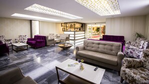 A spacious lobby with a modern design, featuring a mix of seating areas, a reception desk, and a bar/lounge area. - Hotel Business Han (Nevsehir)
