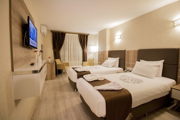 Habitación de hotel con dos camas, un televisor, un escritorio y una silla.