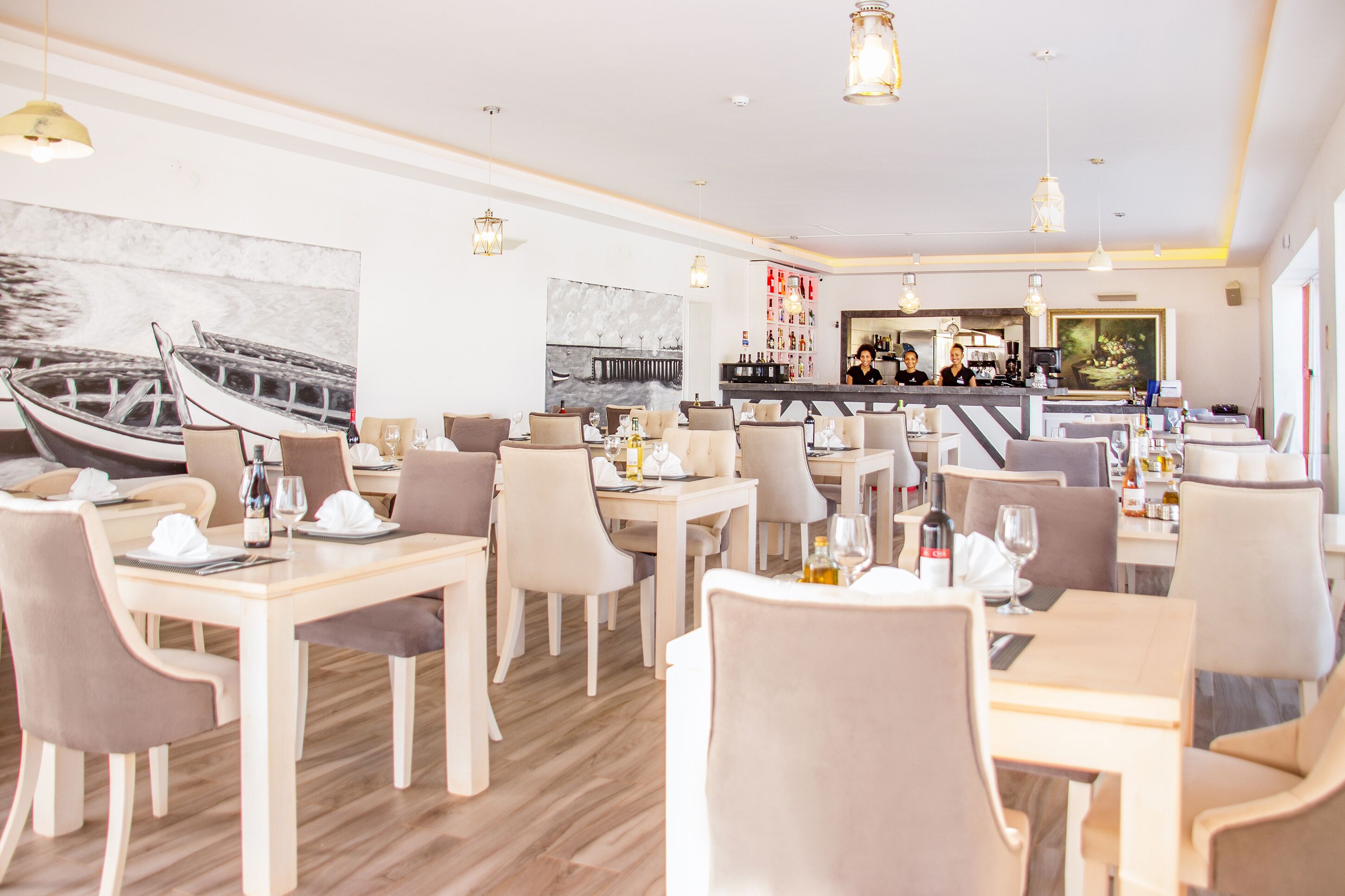 Un restaurant avec des tables et des chaises en bois, un coin bar et des œuvres d’art accrochées aux murs.