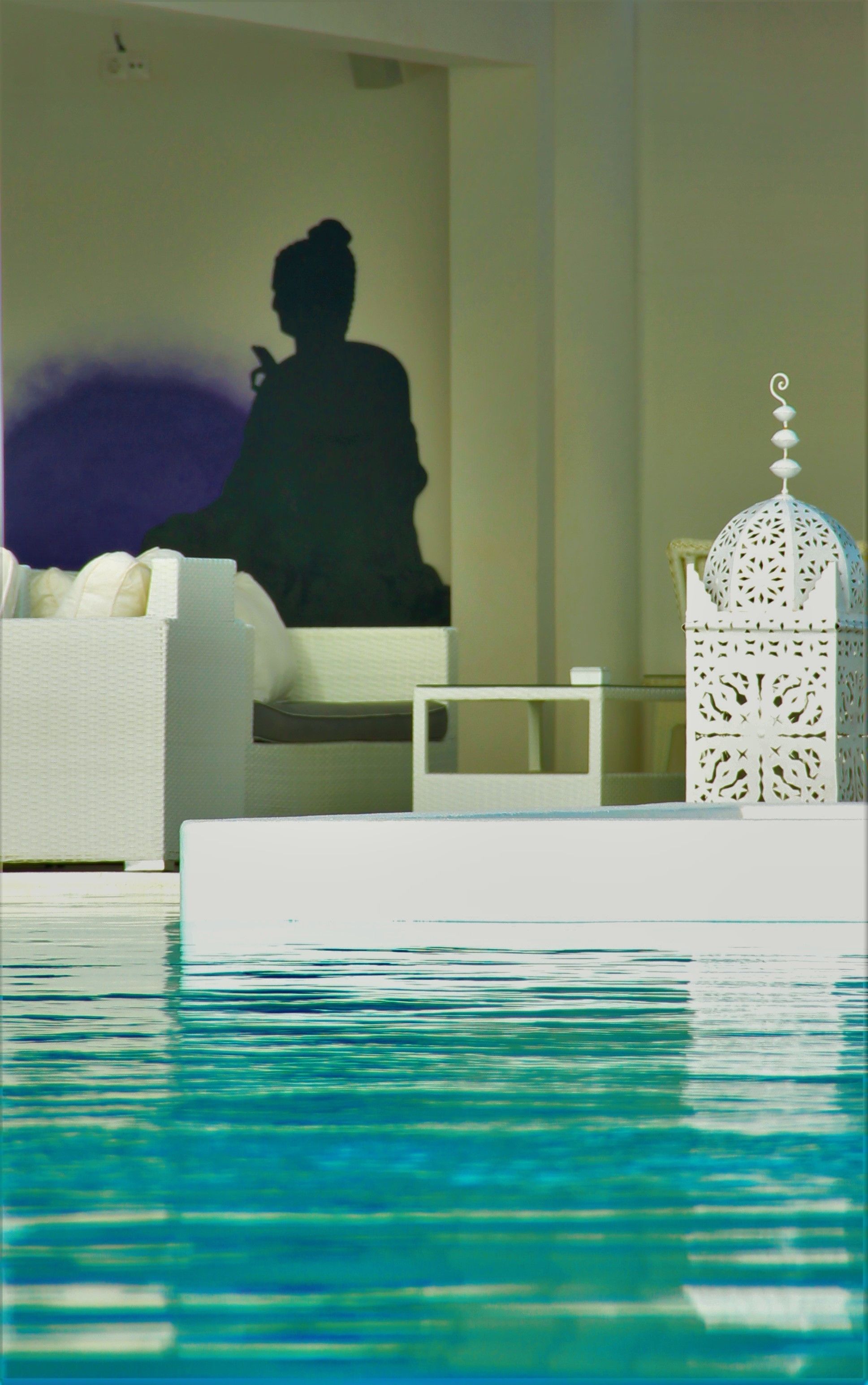 A modern interior with a pool, a white sofa, and a decorative white structure.