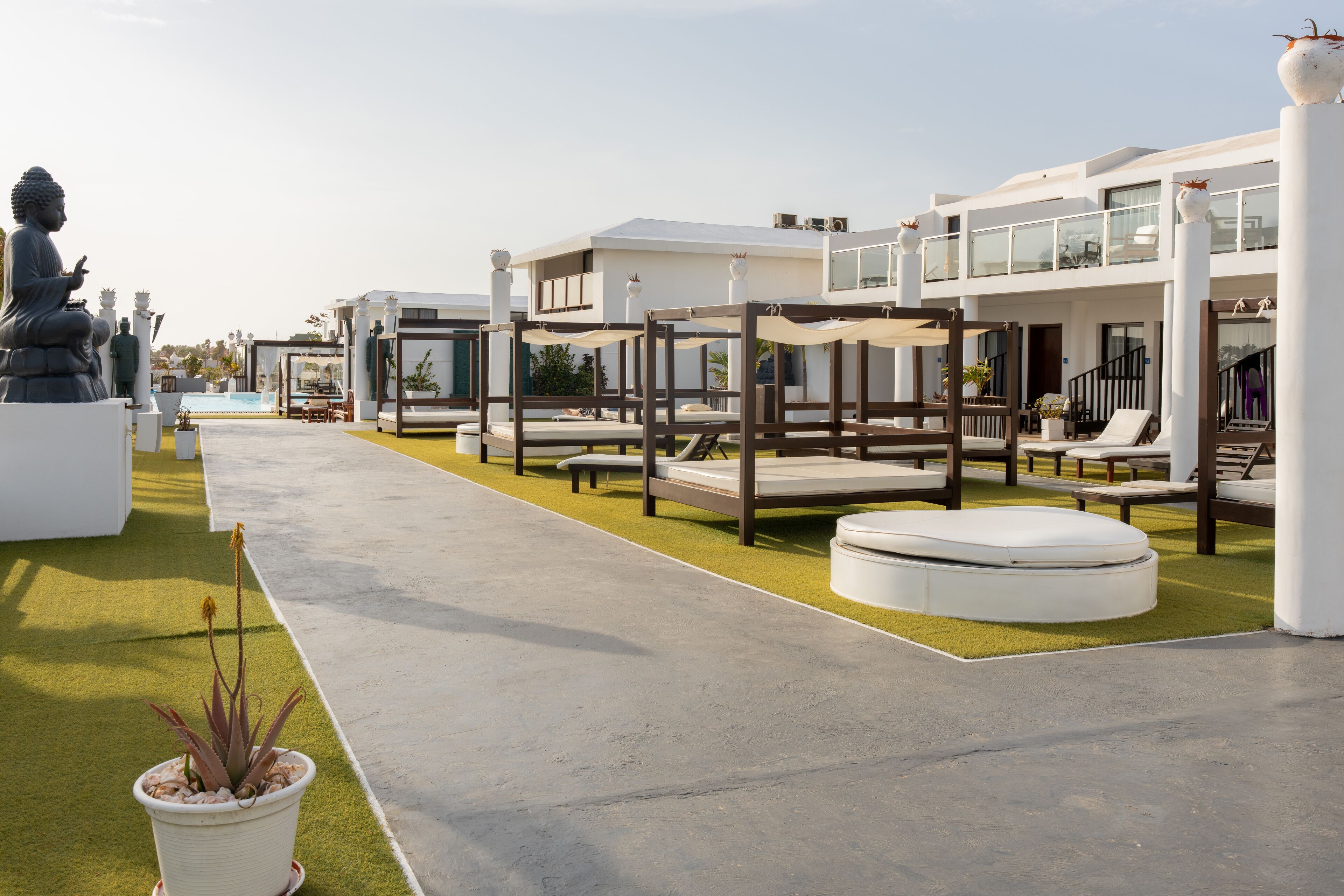 A modern hotel with outdoor seating areas, a Buddha statue, and a pool.