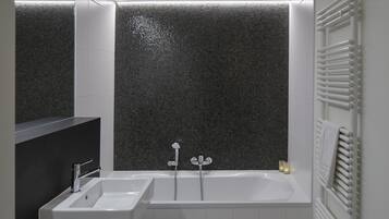 Un baño moderno con un lavamanos blanco, una bañera y un inodoro.