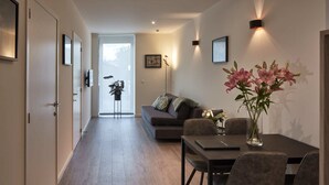 Un salon moderne avec un canapé, une table à manger et des chaises, ainsi qu’un vase de fleurs.