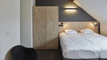 A bedroom with a bed, a wardrobe, and a chair.