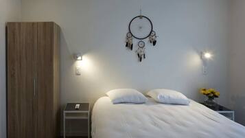 Una camera da letto con un letto, comodini, un armadio, un acchiappasogni, applique e un vaso con fiori.