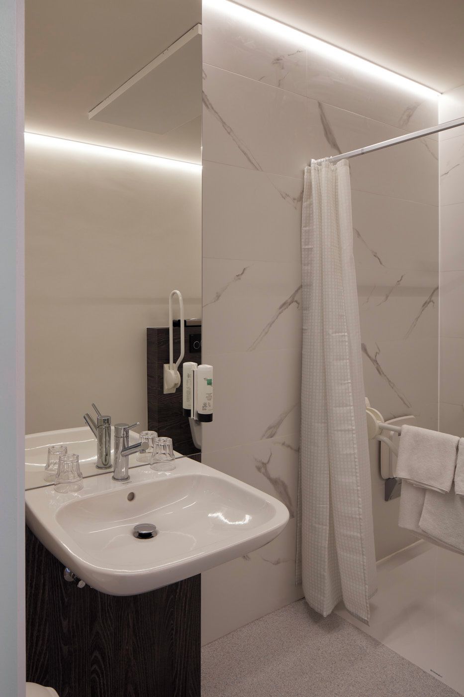 A modern bathroom with a white sink, a mirror, a shower curtain, and a towel rack.