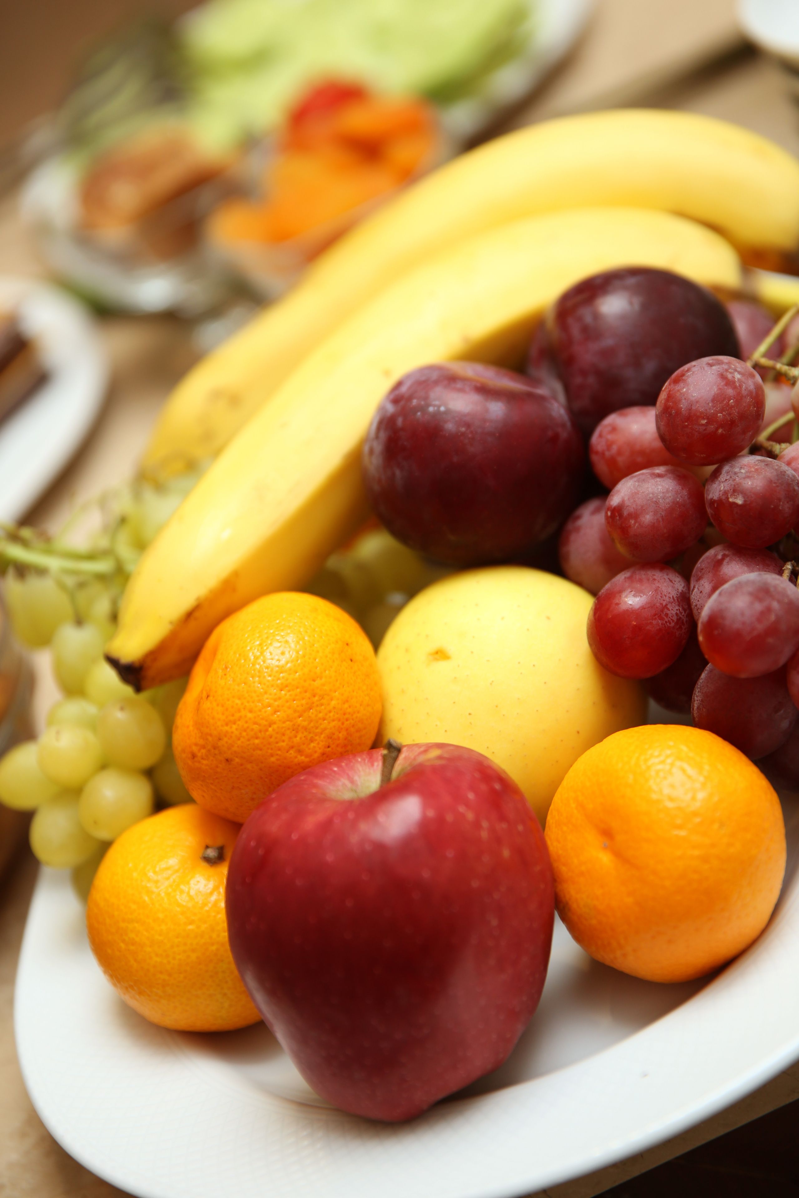 Um prato com uma variedade de frutas, incluindo bananas, uvas, laranjas e maçãs.