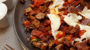 A pan with a dish containing meat and vegetables, a fork, and a plate with a lid.