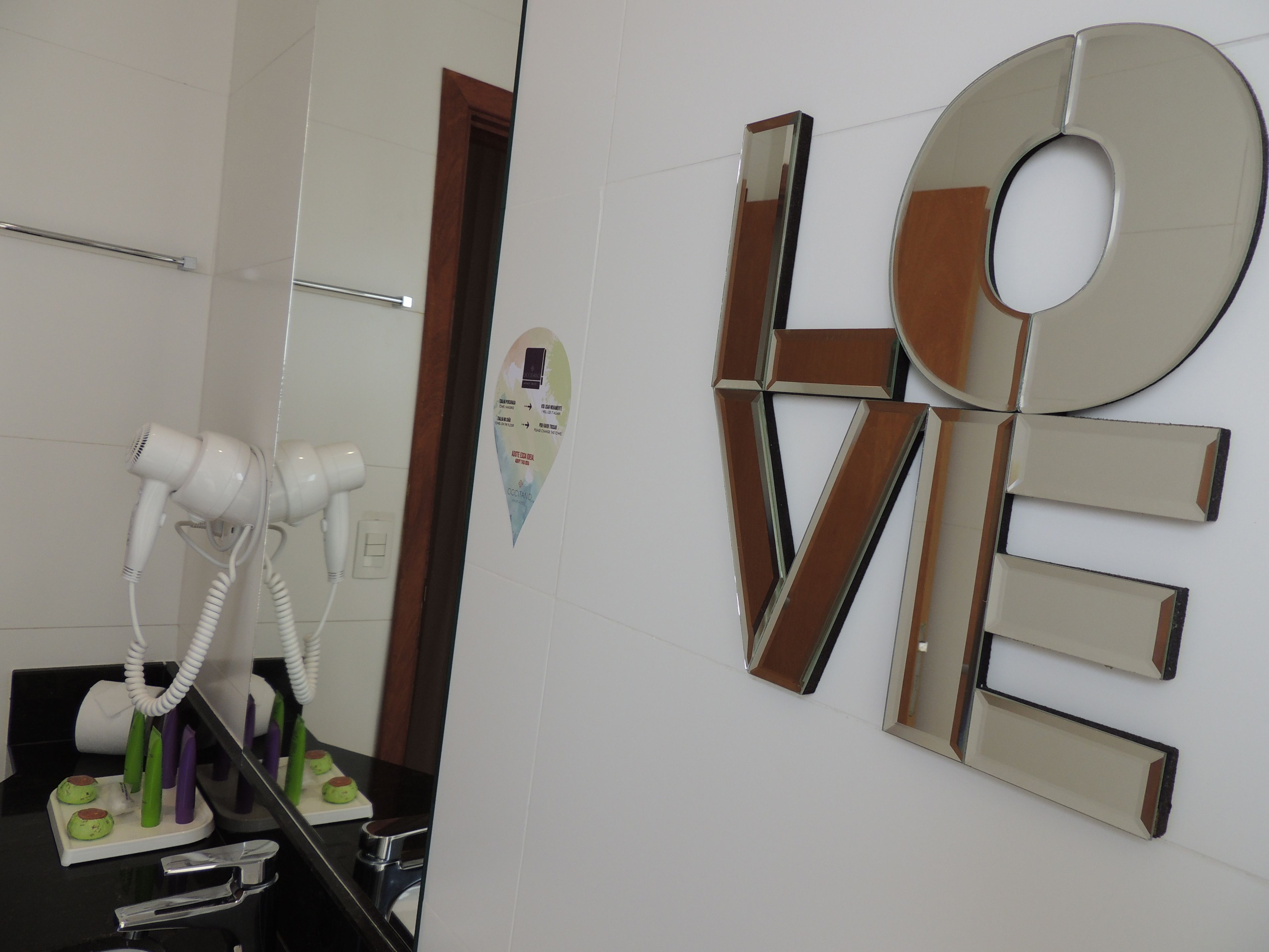 A bathroom with a hairdryer, a mirror, and a wall decoration.