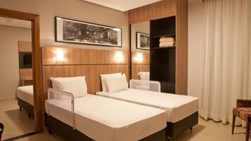 Habitación de hotel con dos camas individuales, cabecero de madera, un espejo grande y un armario.