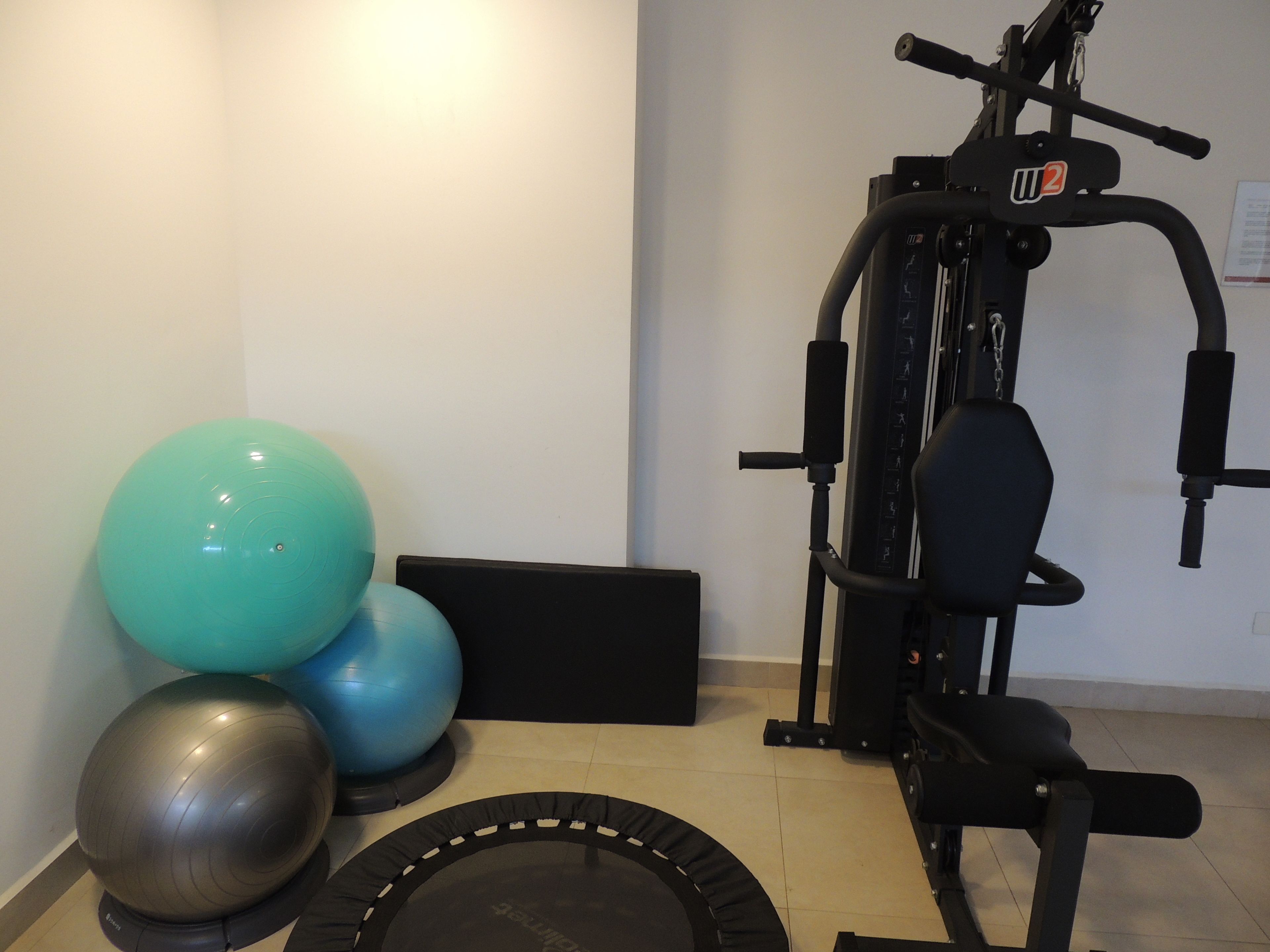A home gym with exercise equipment, including a bench press, a medicine ball, and a trampoline.