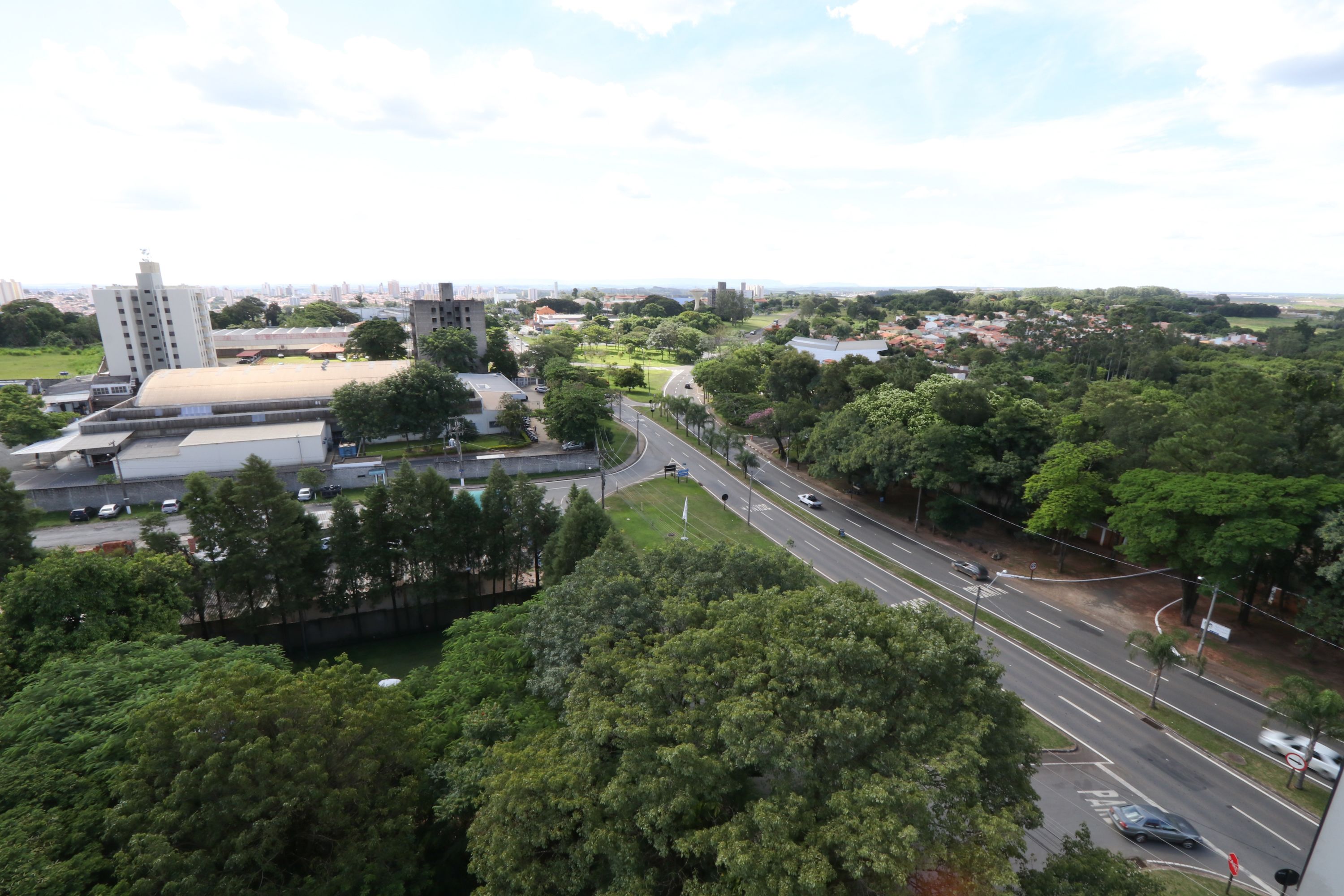 A cityscape with a prominent building, a road with vehicles, and surrounding greenery.