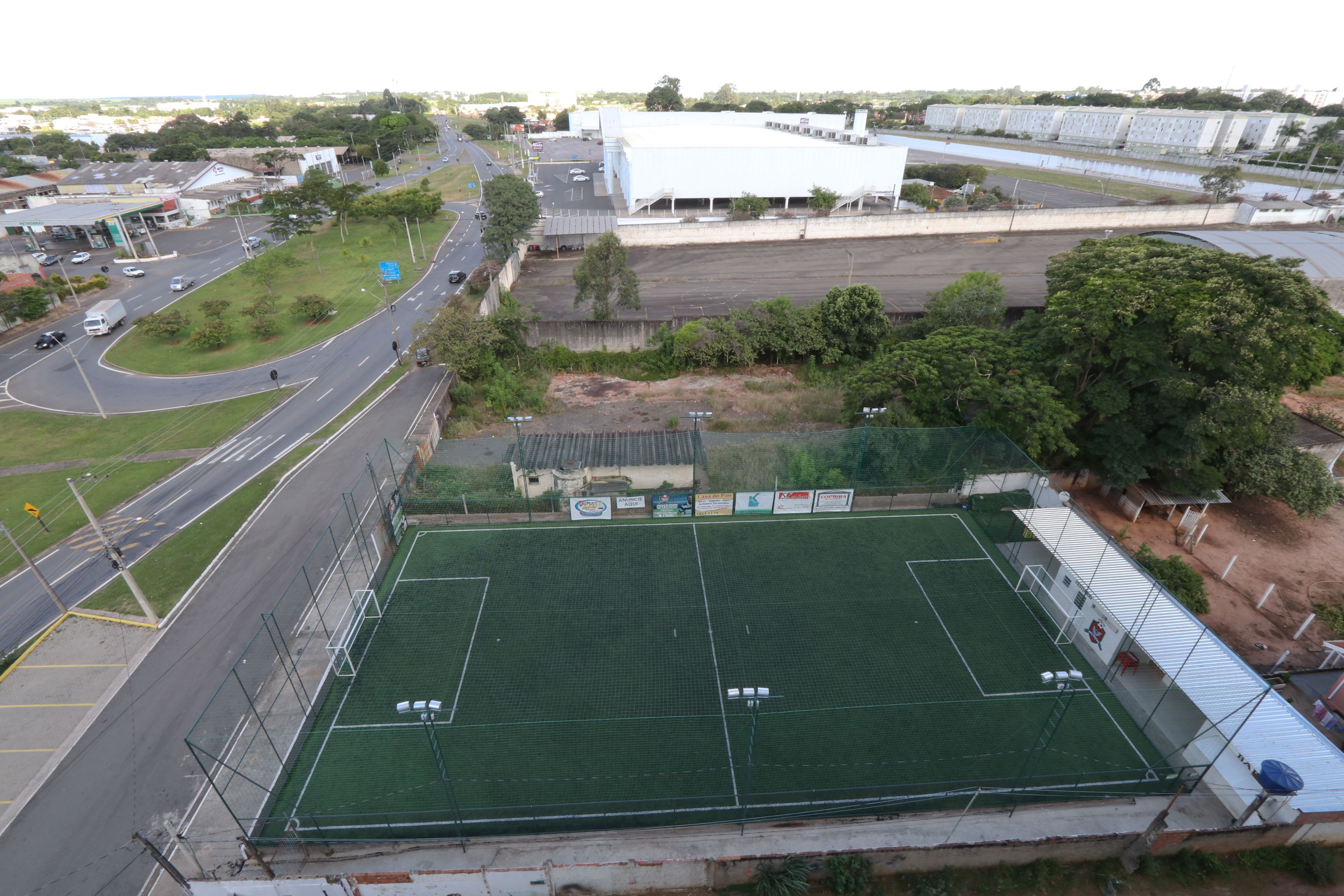 Un amplio campo deportivo con un perímetro cercado, rodeado de calles y edificios.