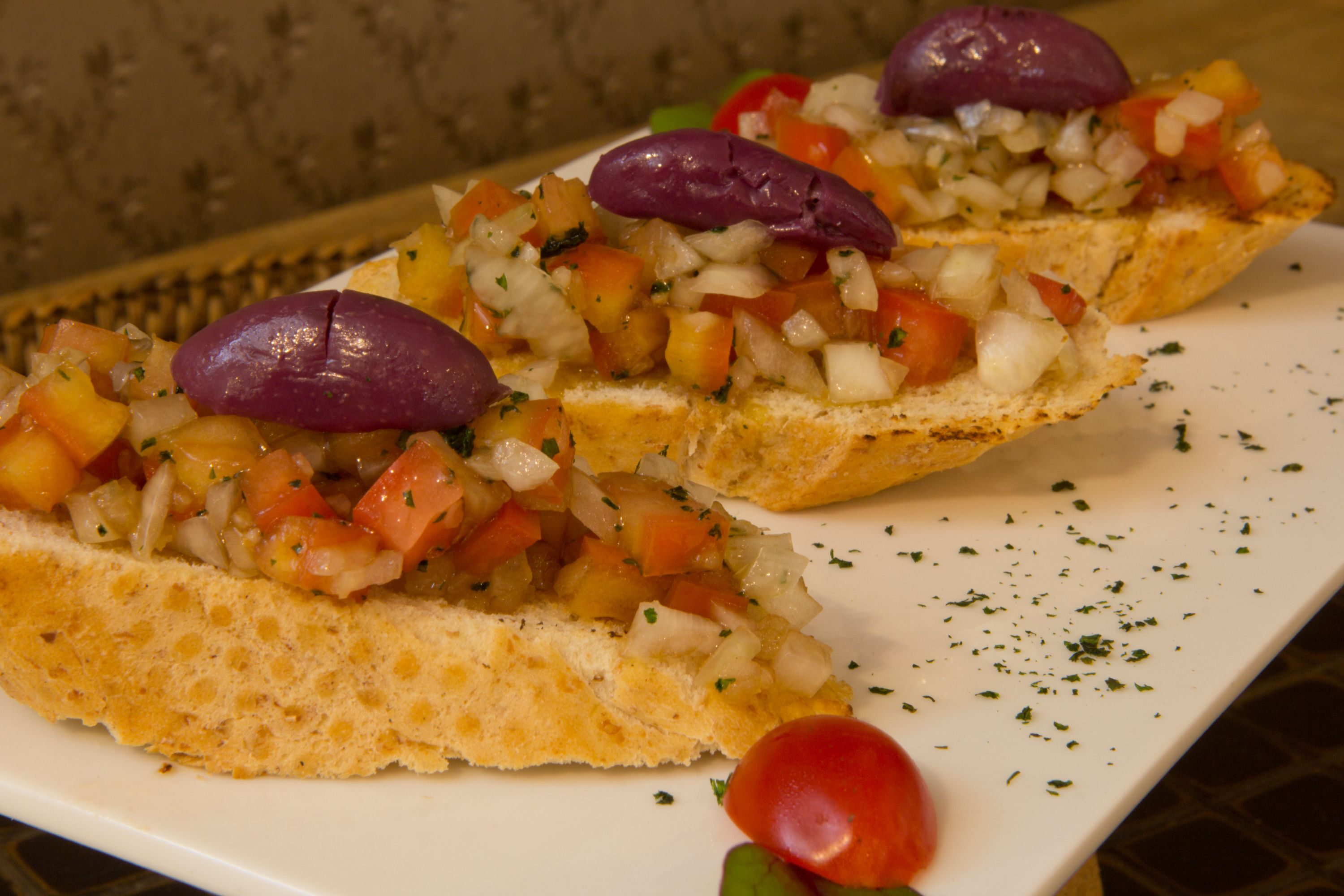 A plate of bruschetta topped with diced tomatoes, onions, and olives.