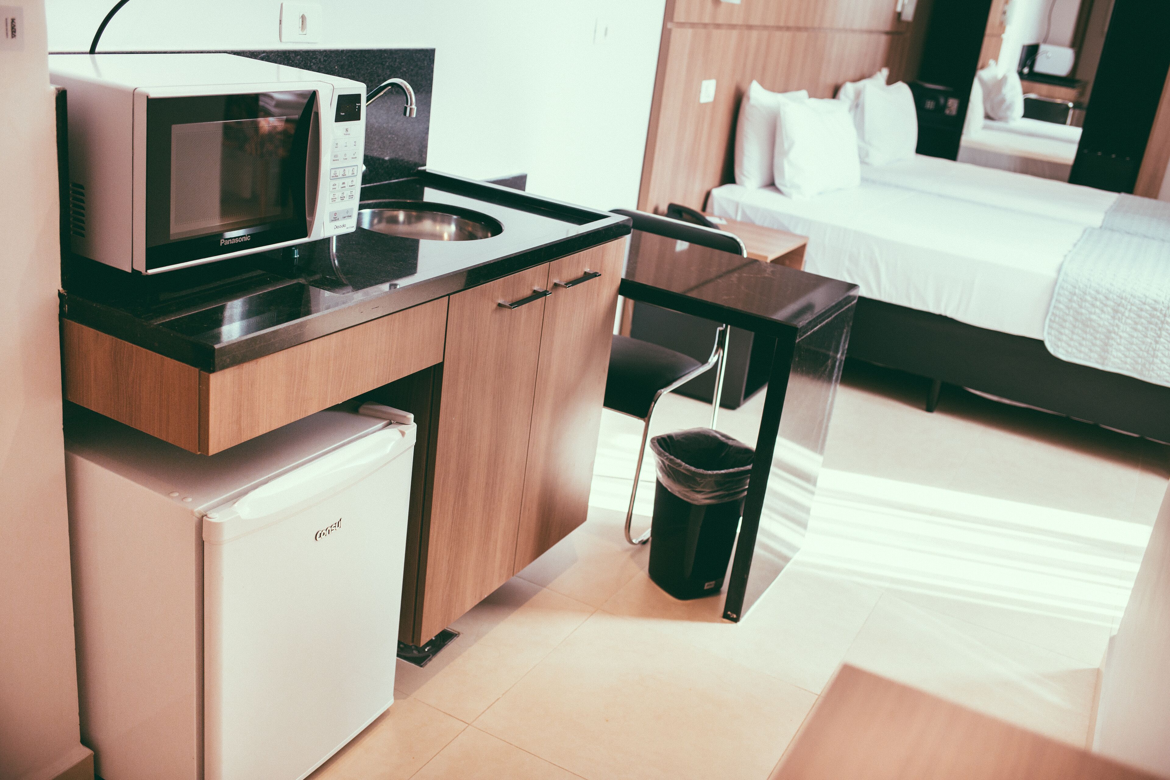Uma cozinha compacta com micro-ondas, geladeira e pia.