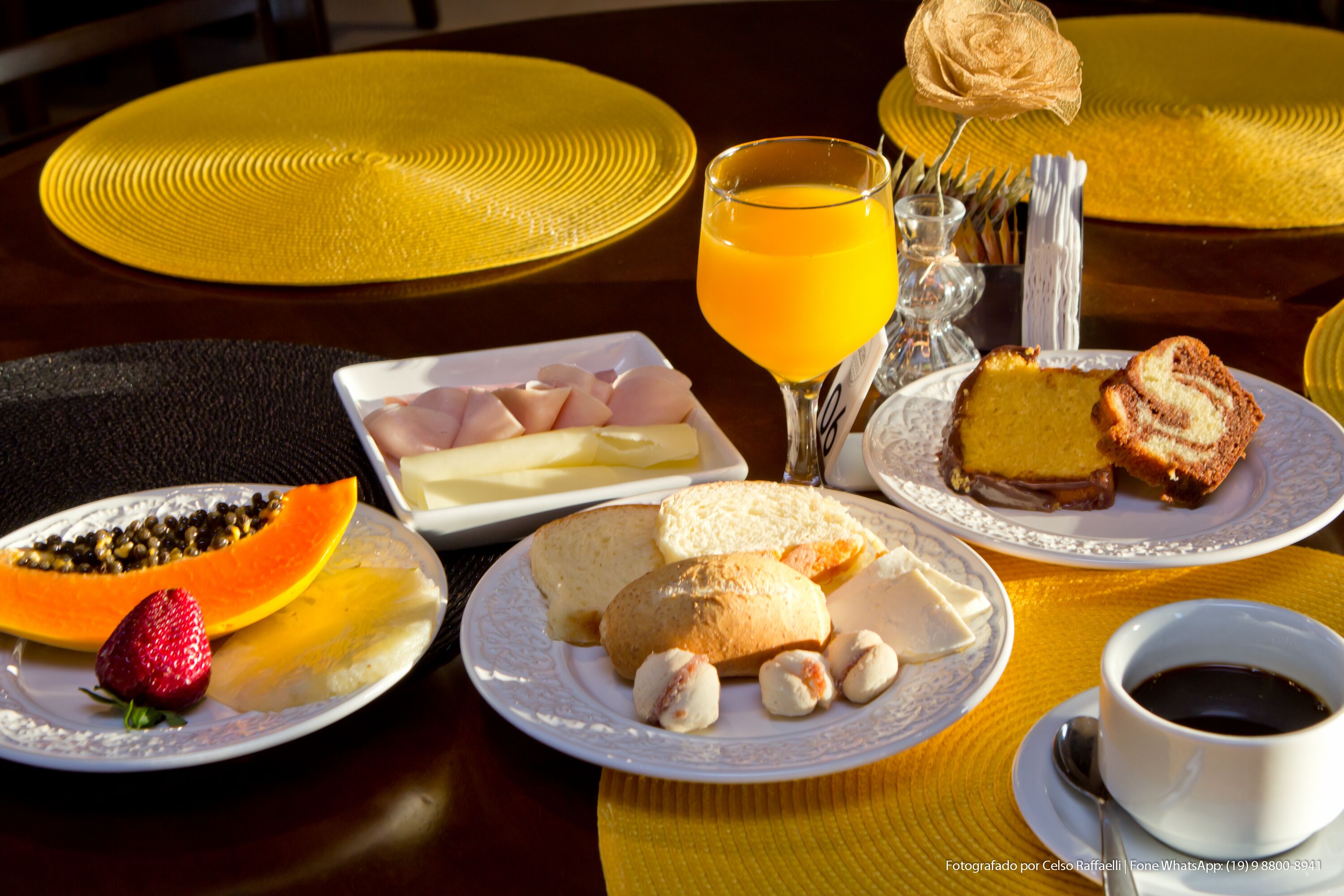 Une table de petit-déjeuner avec des assiettes remplies de nourriture, un verre de jus d’orange et une tasse de café.