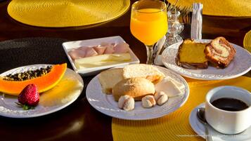 Une table de petit-déjeuner avec des assiettes remplies de nourriture, un verre de jus d’orange et une tasse de café.