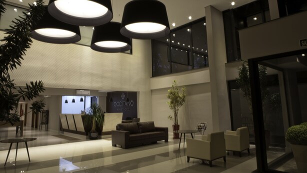 Un moderno vestíbulo de hotel con mostrador de recepción, zona de estar y ventanas amplias.