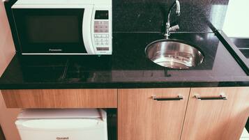 A compact kitchen with a microwave, sink, and a refrigerator.