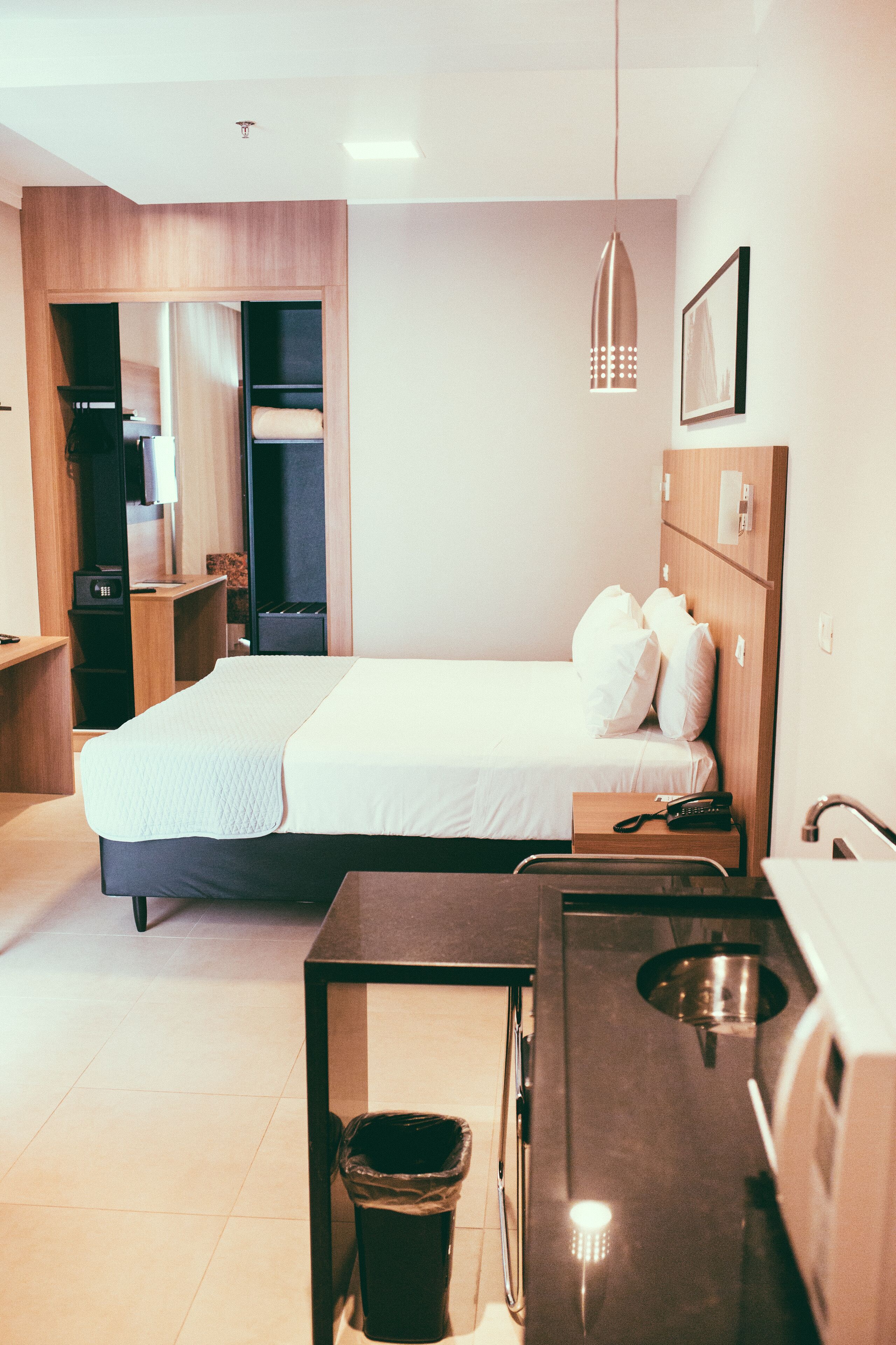 Une chambre d’hôtel moderne équipée d’un lit, d’une table de chevet et d’un petit bureau.