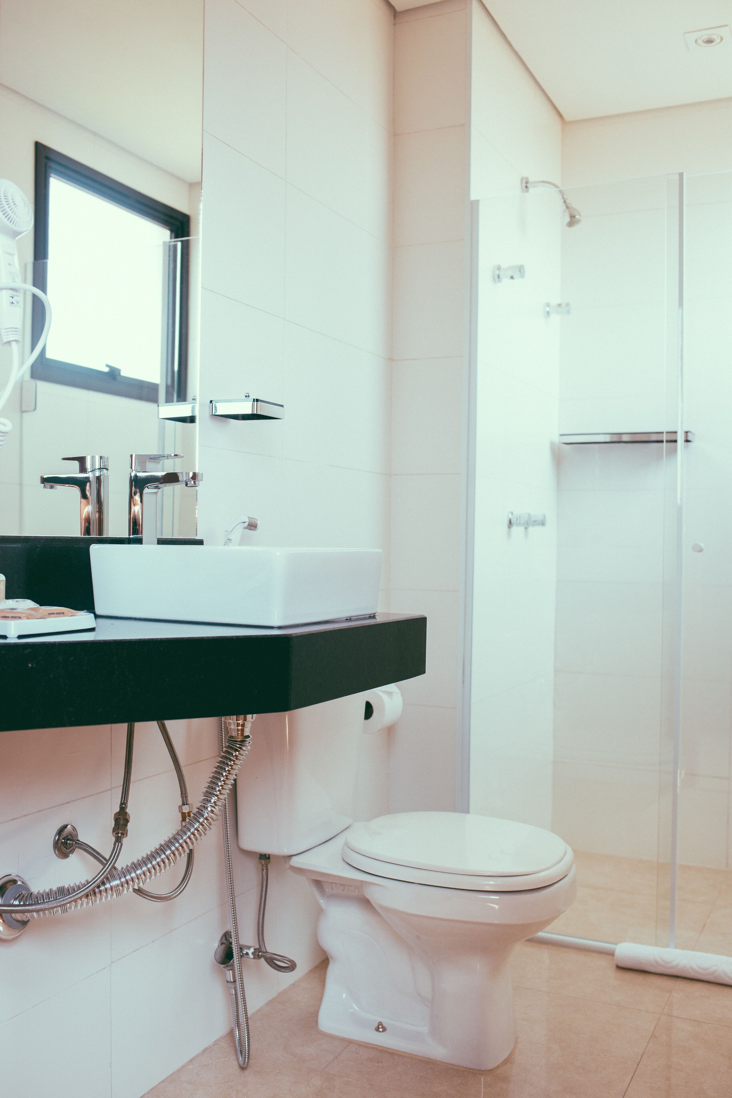 A modern bathroom with a white sink, a toilet, and a glass shower enclosure.