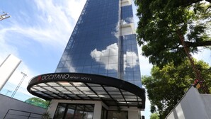 El exterior del OCCITANO APART HOTEL, con una fachada moderna de vidrio y un dosel curvo en la entrada.