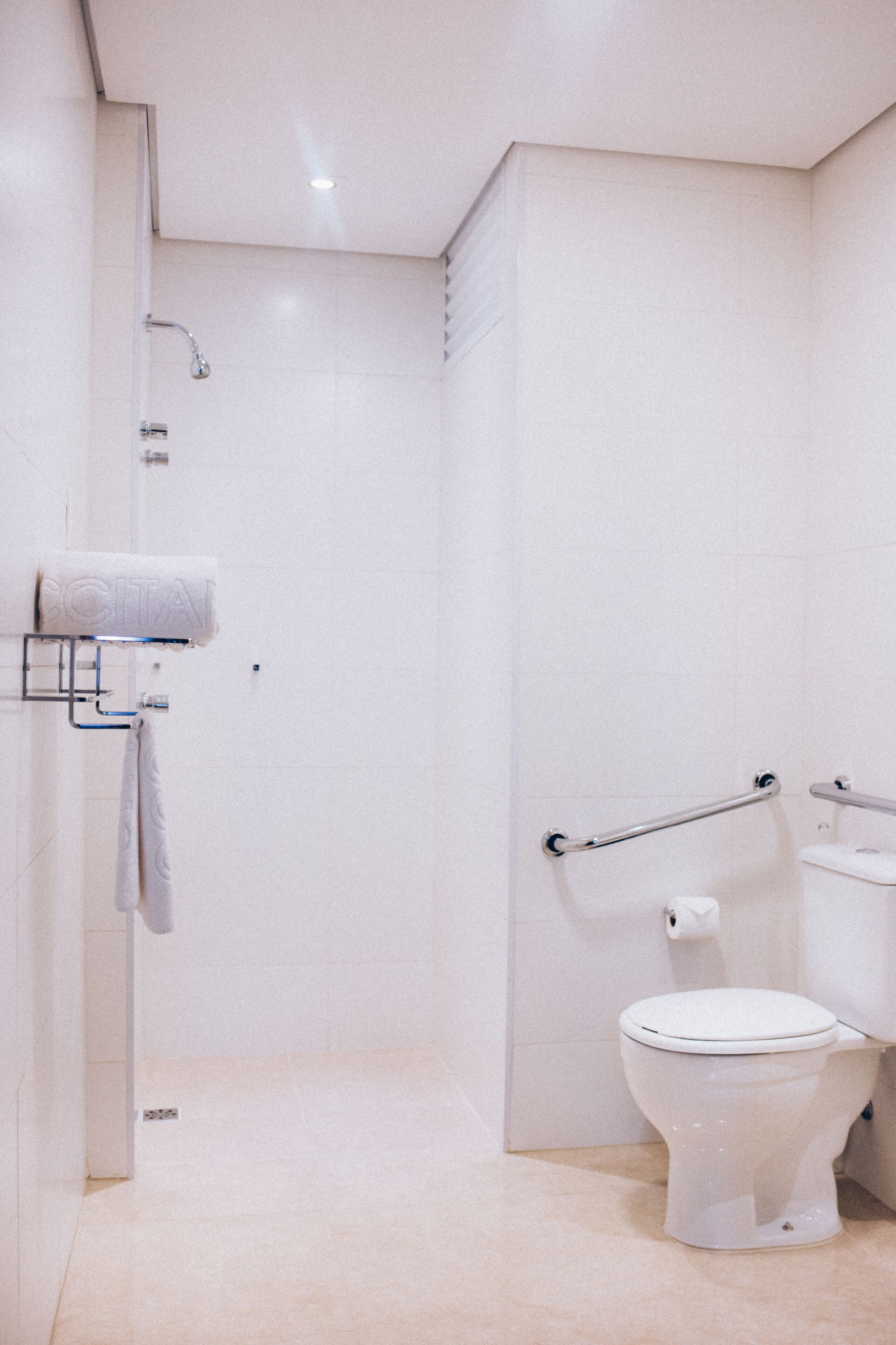Un baño moderno con inodoro, ducha y perchero.