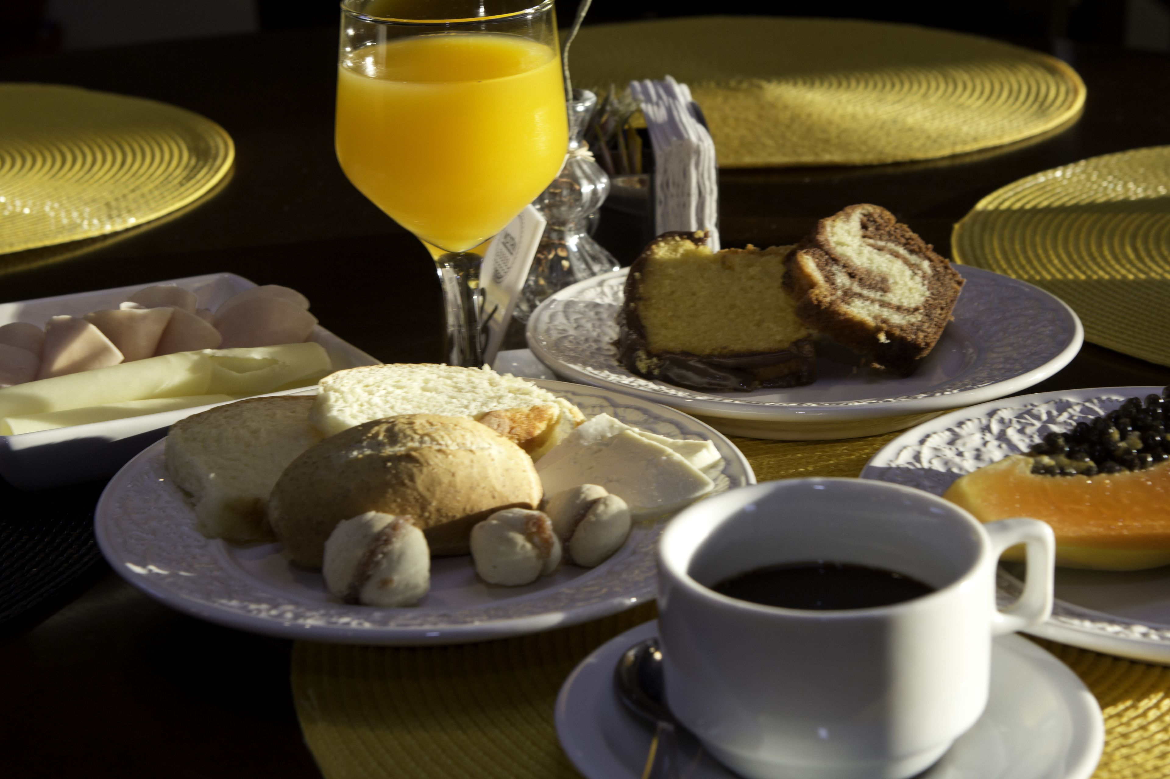 A breakfast setting with plates of pastries, a glass of orange juice, and a cup of coffee.