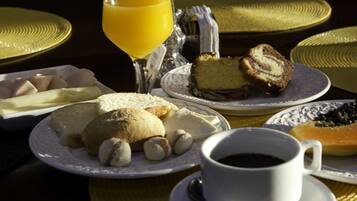 A breakfast setting with plates of pastries, a glass of orange juice, and a cup of coffee.
