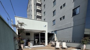 Un área de piscina moderna al aire libre, con una piscina azul cristalina, rodeada de sillas de descanso y un espacio de estar cubierto.