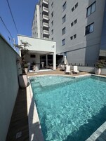 Una piscina al aire libre, sombrillas, sillones reclinables de piscina