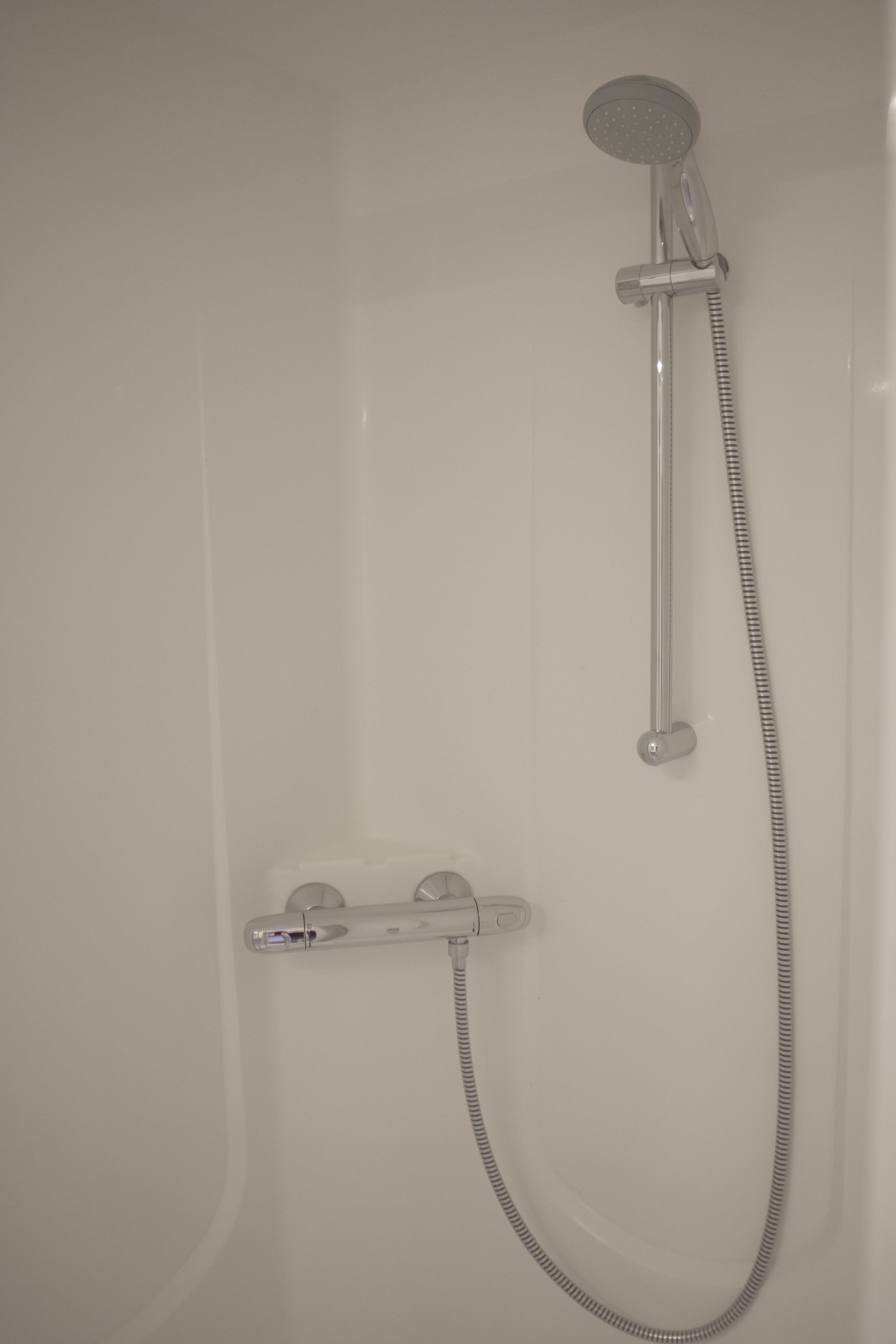 A modern shower with a handheld showerhead and a flexible hose.