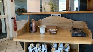 Interior de uma cafeteria com balcão de madeira, máquina de café expresso e quadro de menu.