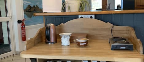 Interior de uma cafeteria com balcão de madeira, máquina de café expresso e quadro de menu.