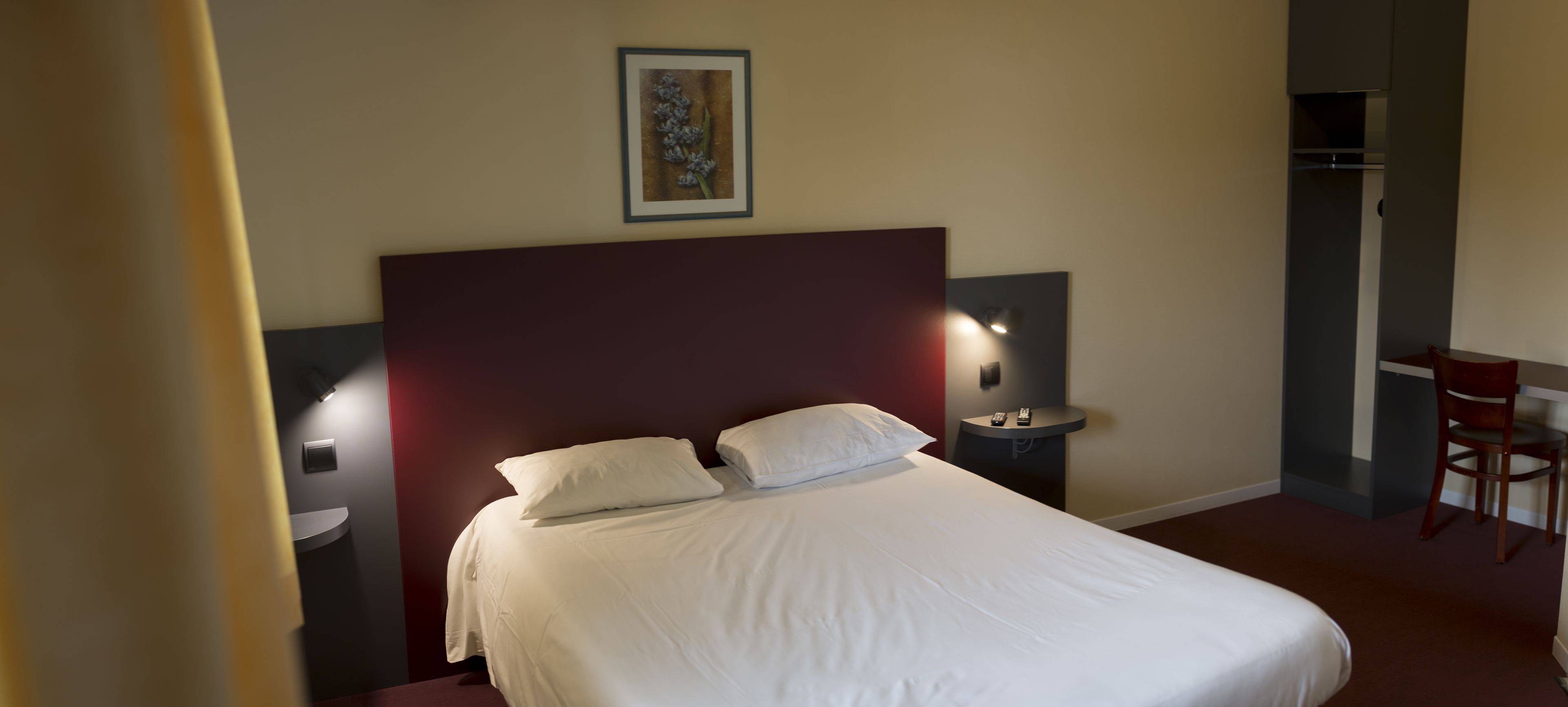 Una habitación de hotel con una cama grande, dos mesitas de noche, un escritorio y una silla.