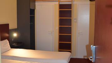 A hotel room with a bed, a wardrobe, a desk, and a TV.