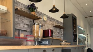 Cozinha moderna com armários cinza, bancada de madeira e luminárias pendentes.