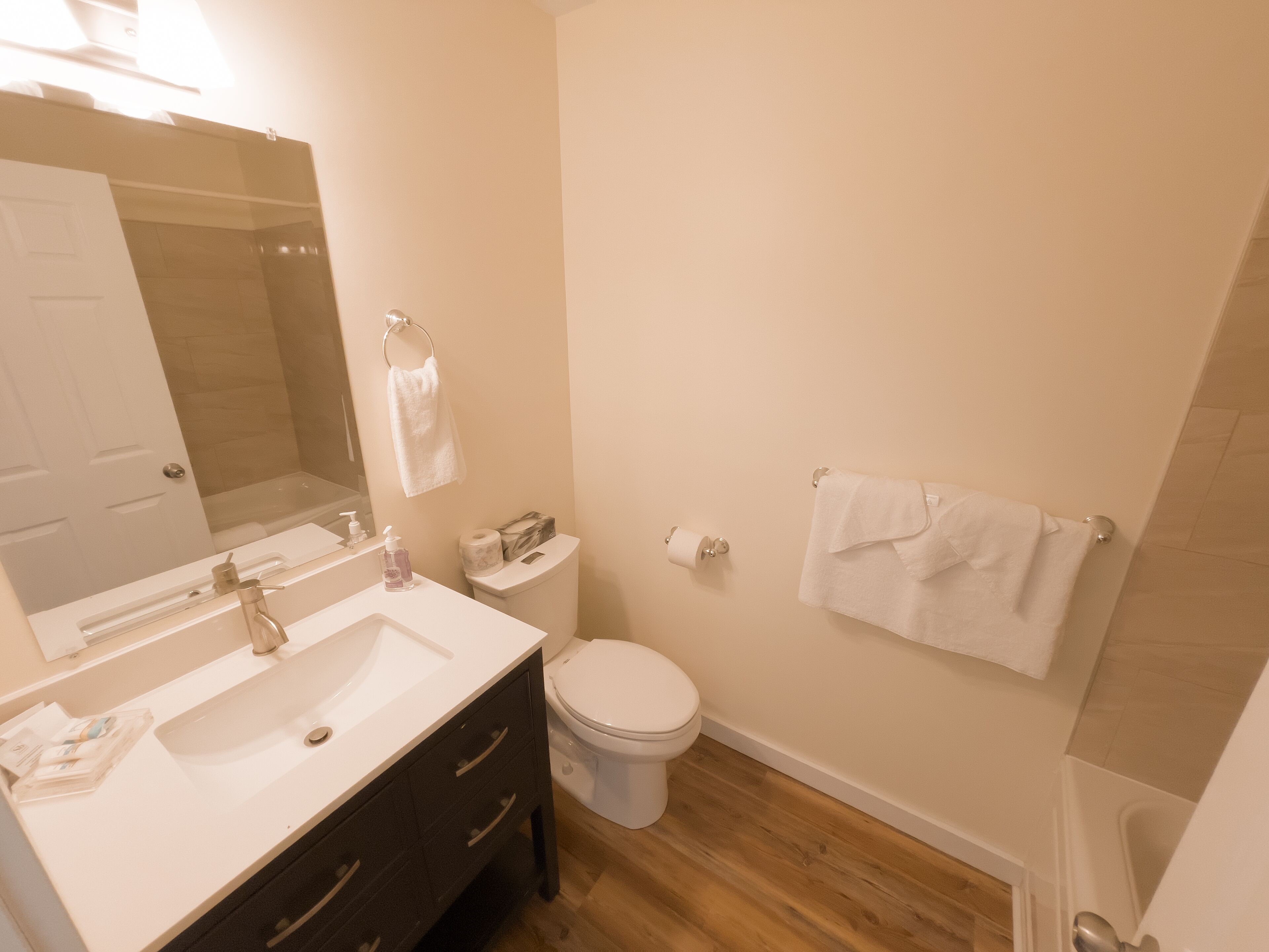 A bathroom with a sink, mirror, toilet, and towel rack.
