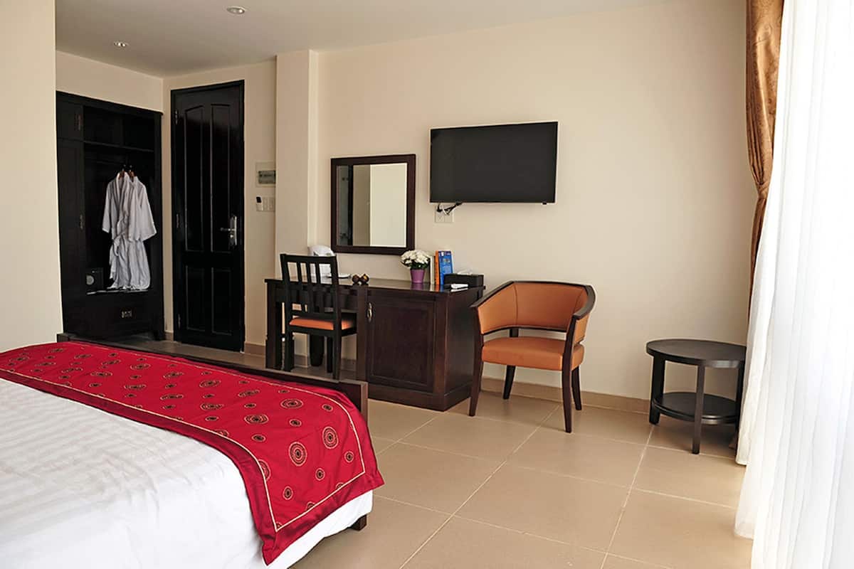 A hotel room with a bed, a desk, a chair, a TV, and a wardrobe.