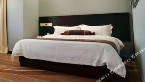 Una habitación de hotel moderna con una cama grande, un cabecero con panel de control y piso de madera.