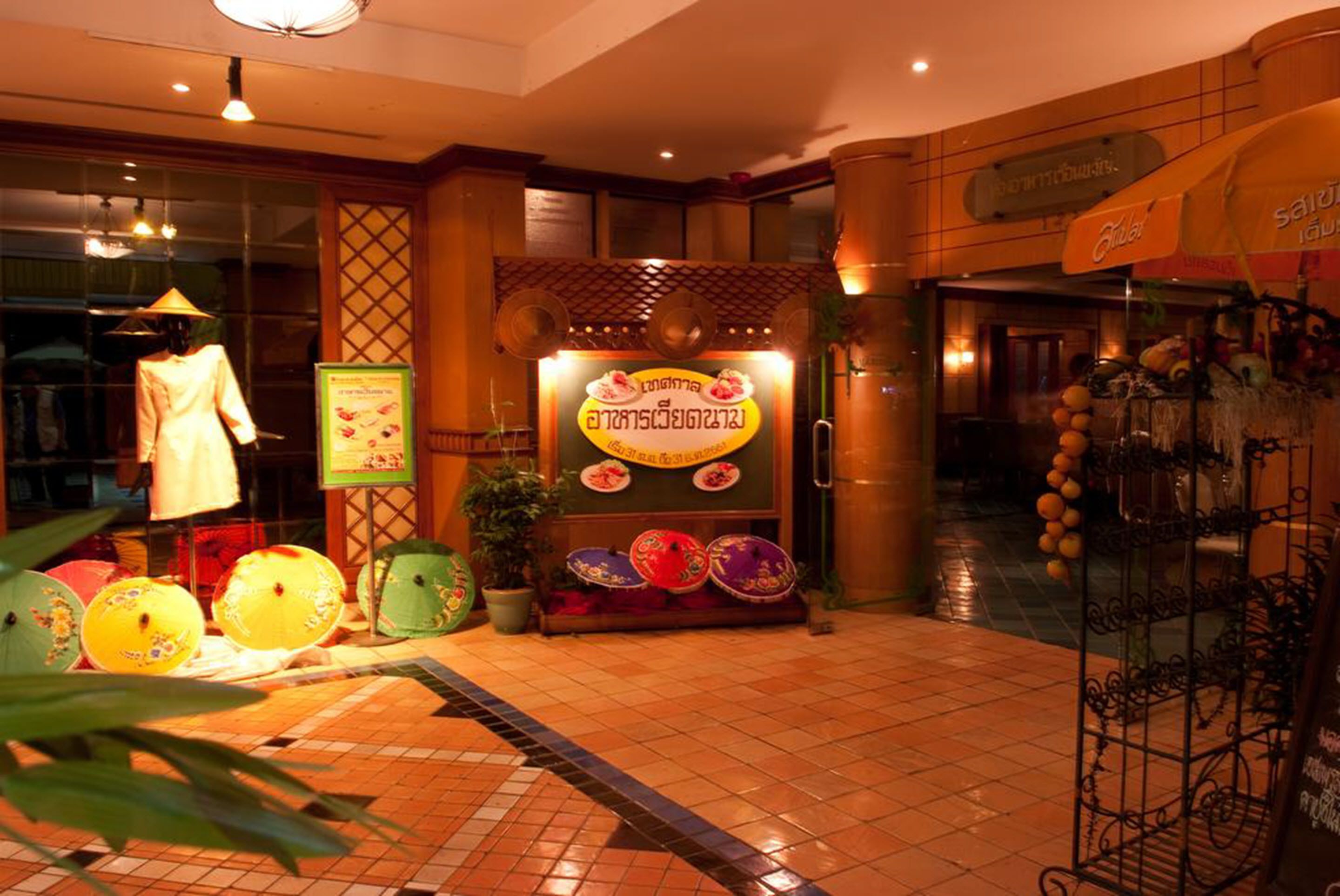 Un restaurant à la décoration d’inspiration asiatique traditionnelle, avec une enseigne indiquant les plats proposés et une exposition de parasols aux couleurs vives.