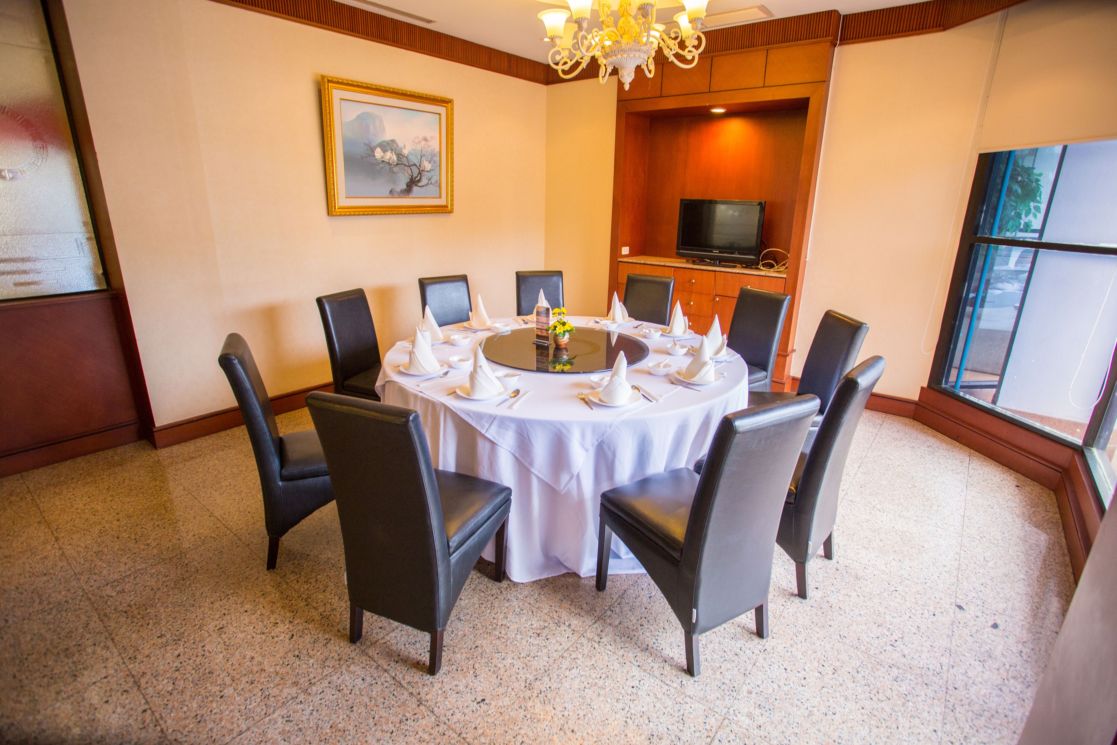 Une salle de conférence avec une table ronde, huit chaises et un téléviseur en arrière-plan.