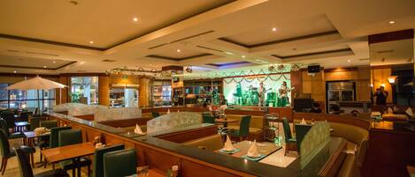 Un restaurante con cabinas y mesas, una zona de bar y vistas a la calle.