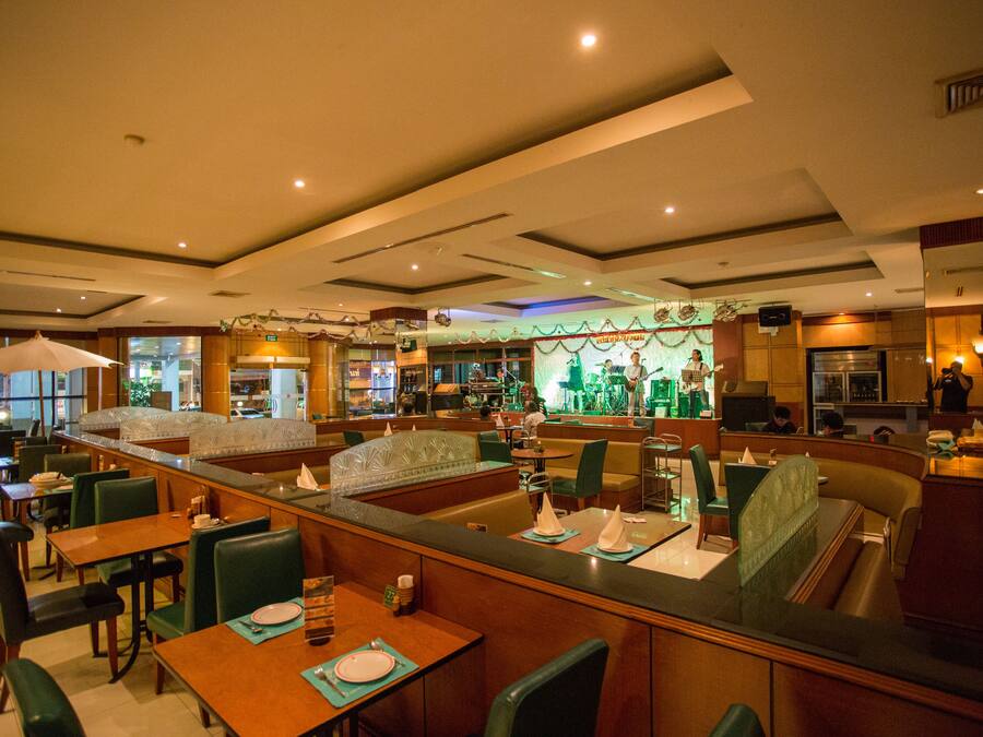 Un restaurante con cabinas y mesas, una zona de bar y vistas a la calle.