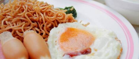 A plate with noodles, a fried egg, and slices of meat.