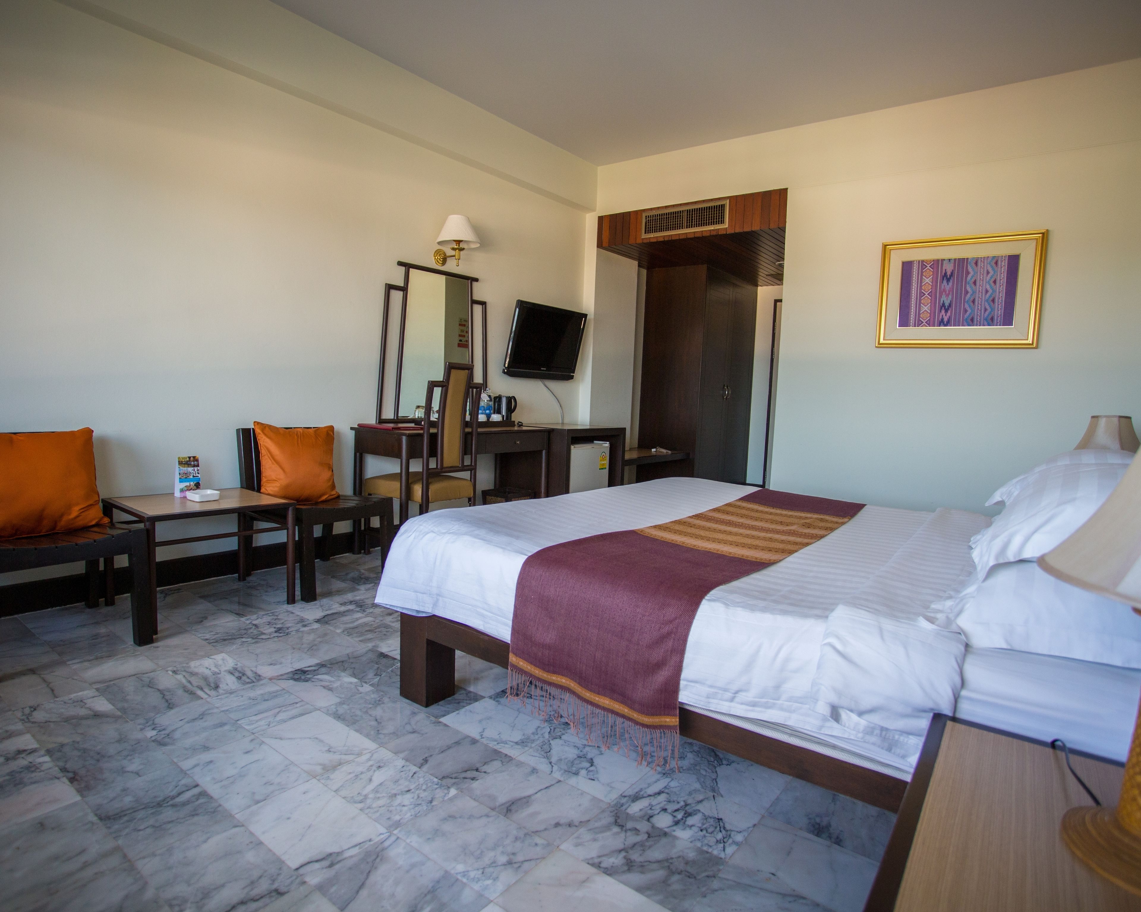 Een hotelkamer met een groot bed, een bureau met stoel, een televisie en een kledingkast.